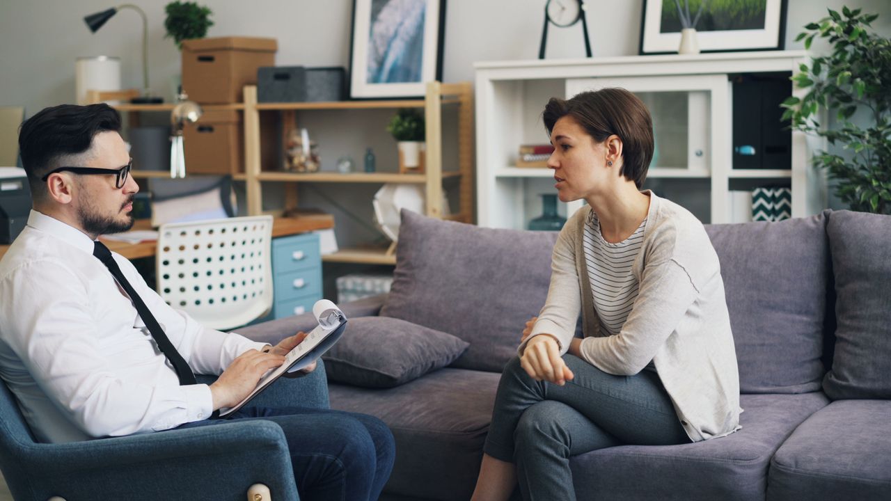 journey A therapist consults with a client during a counseling session on a sofa in an office setting.
