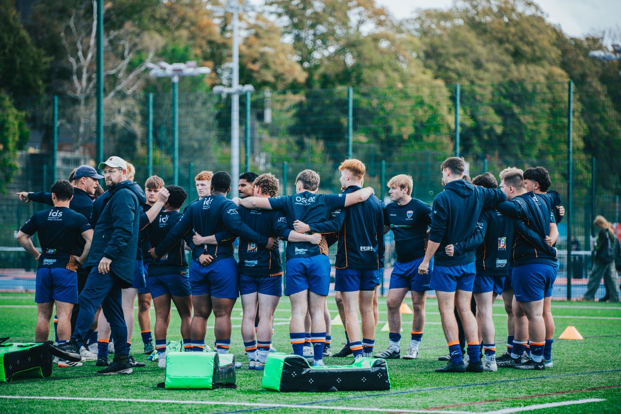 team-02 Rugby team gathers in a huddle on green field, preparing for a match, showcasing team spirit and sportsmanship.