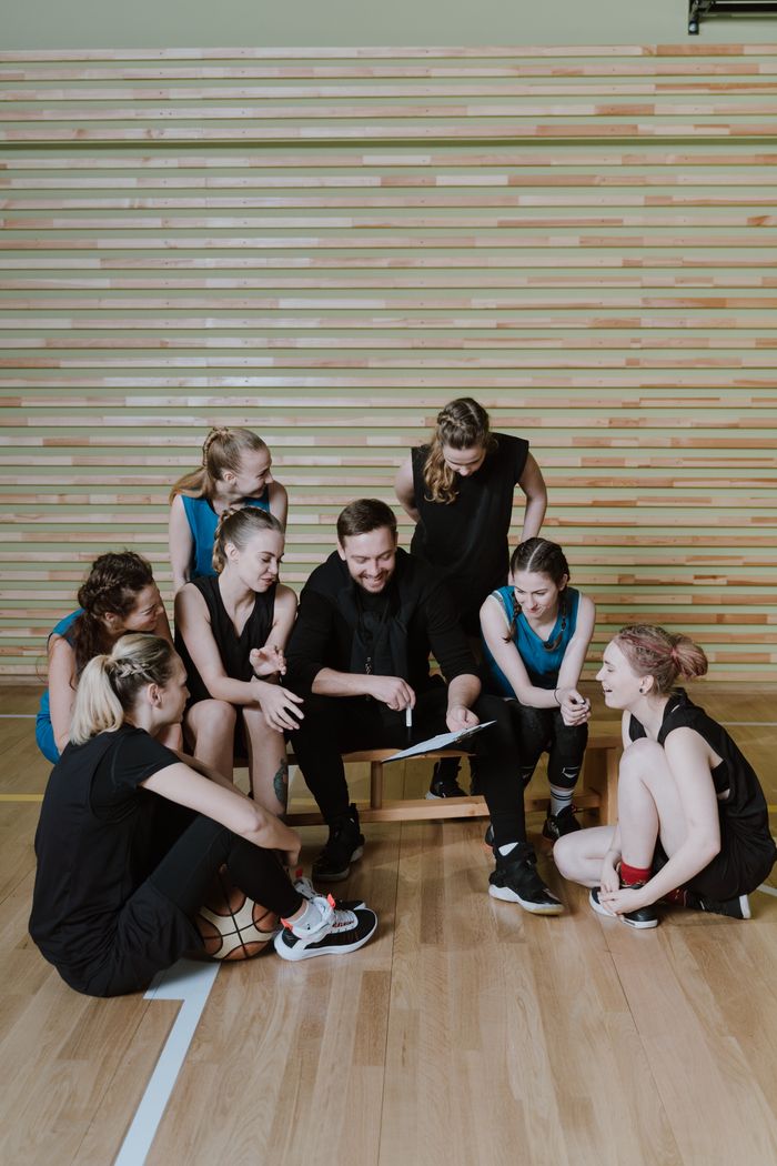 services-03 Basketball team and coach discuss strategies during training in a gymnasium.