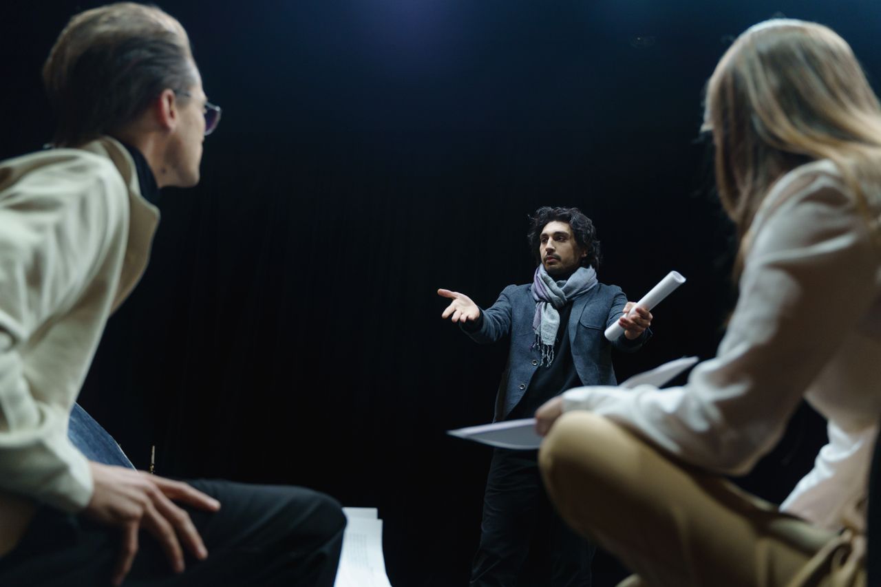 services-04 Theater director guides actors in an intense rehearsal scene on stage.
